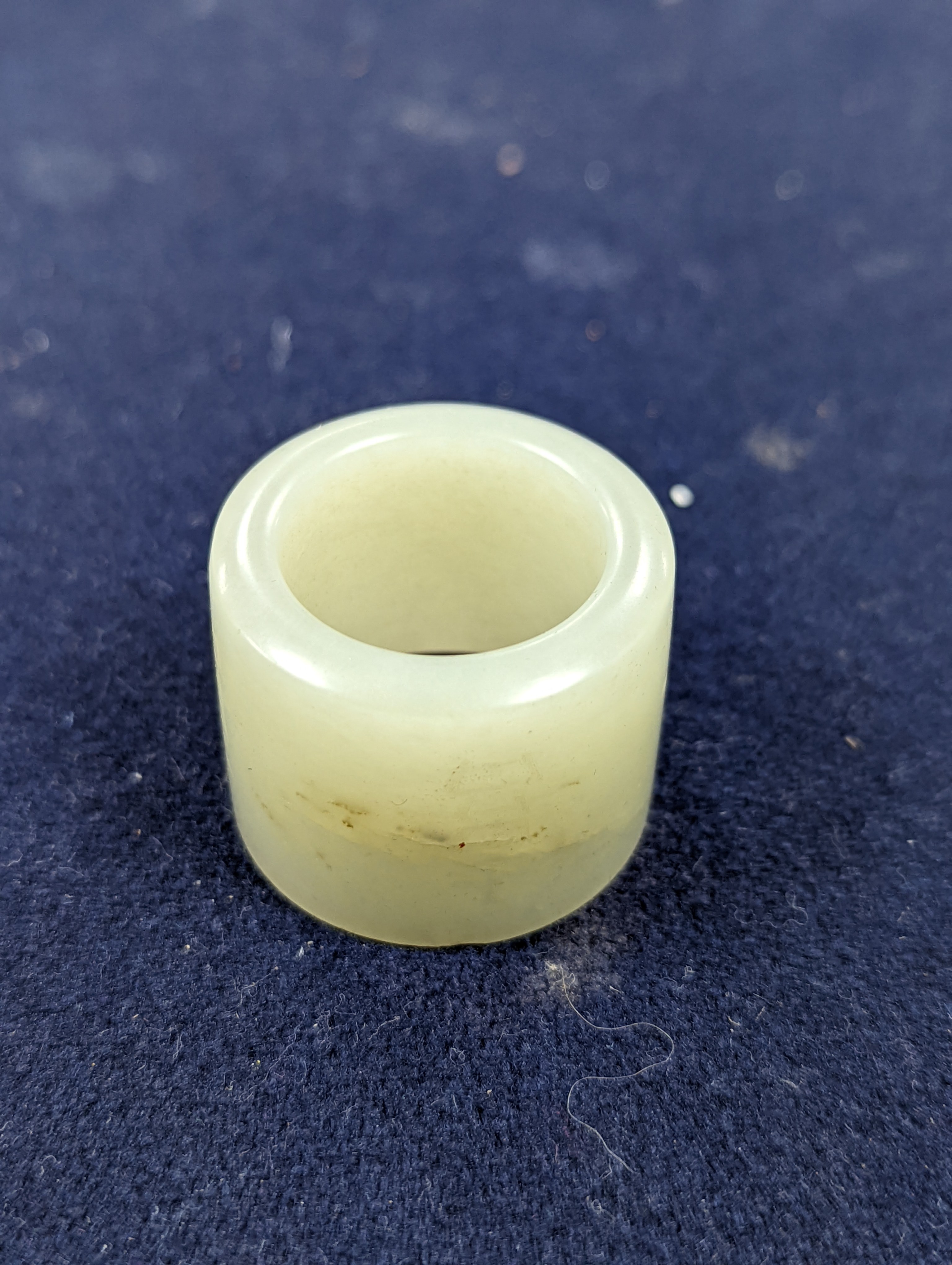 A 19th century Chinese pale celadon jade archer’s thumb ring, inscribed, 3 cm diameter